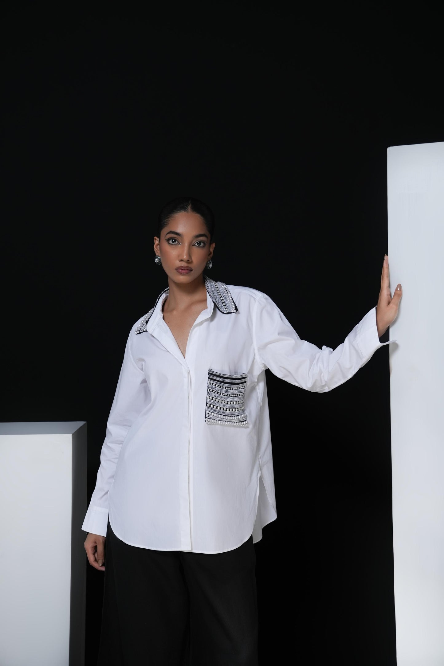 White cotton shirt with pearl detailing on pocket and collar paired with black trousers