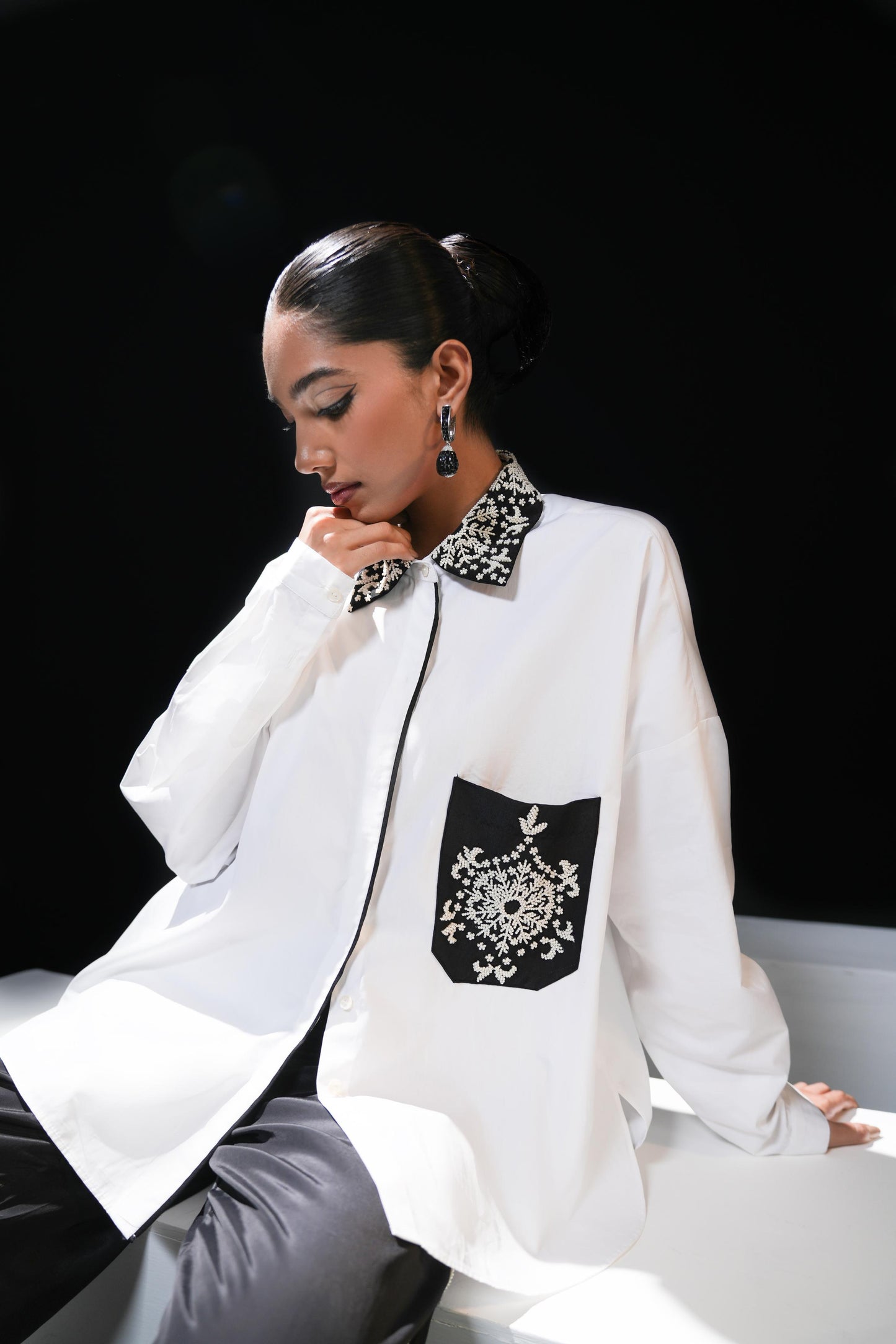 White cotton shirt with pearl detailing on pocket and collar paired with black trousers