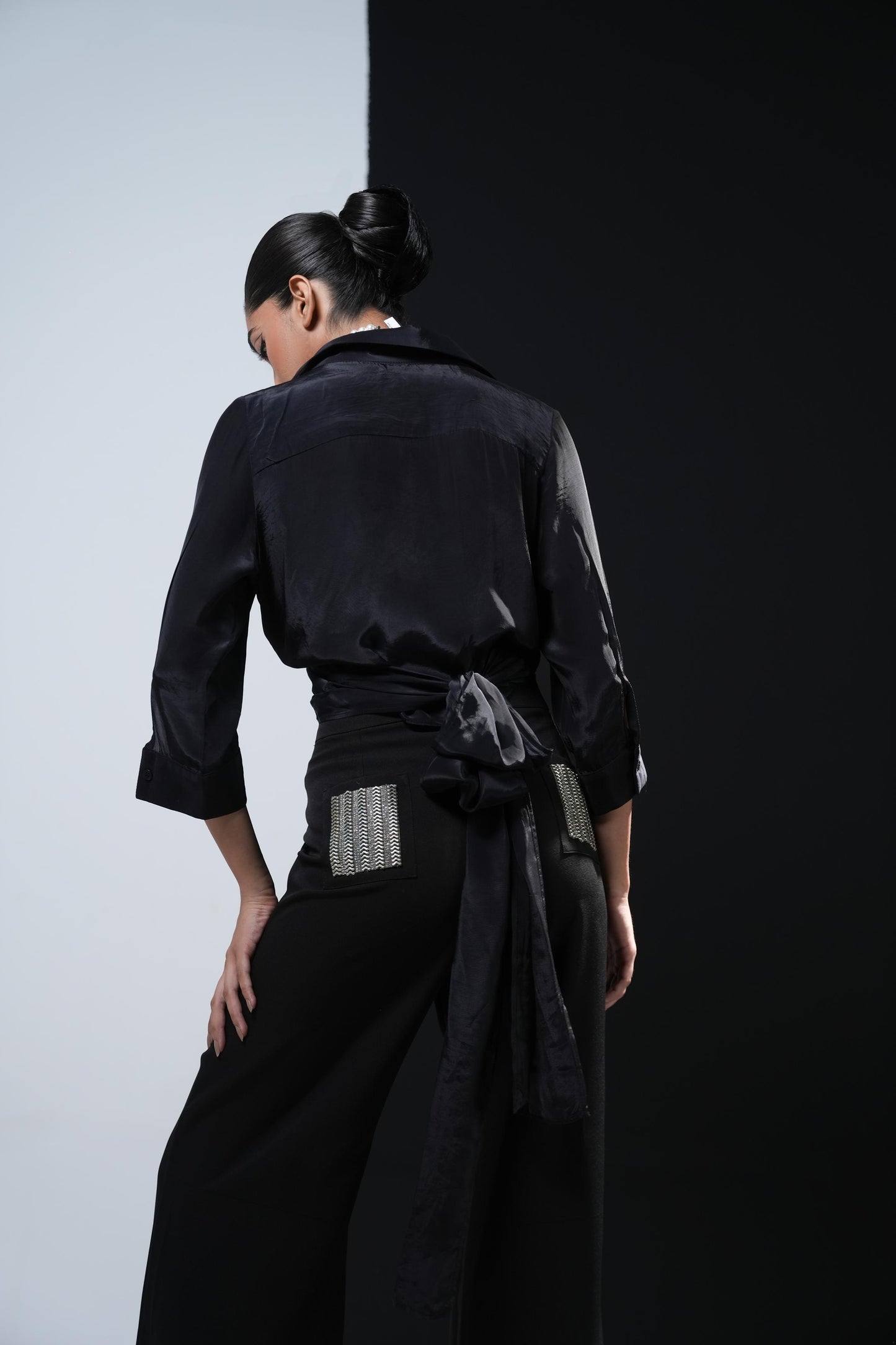 Black crepe overlapping shirt with a long bow paired with black trousers with swaroski pockets