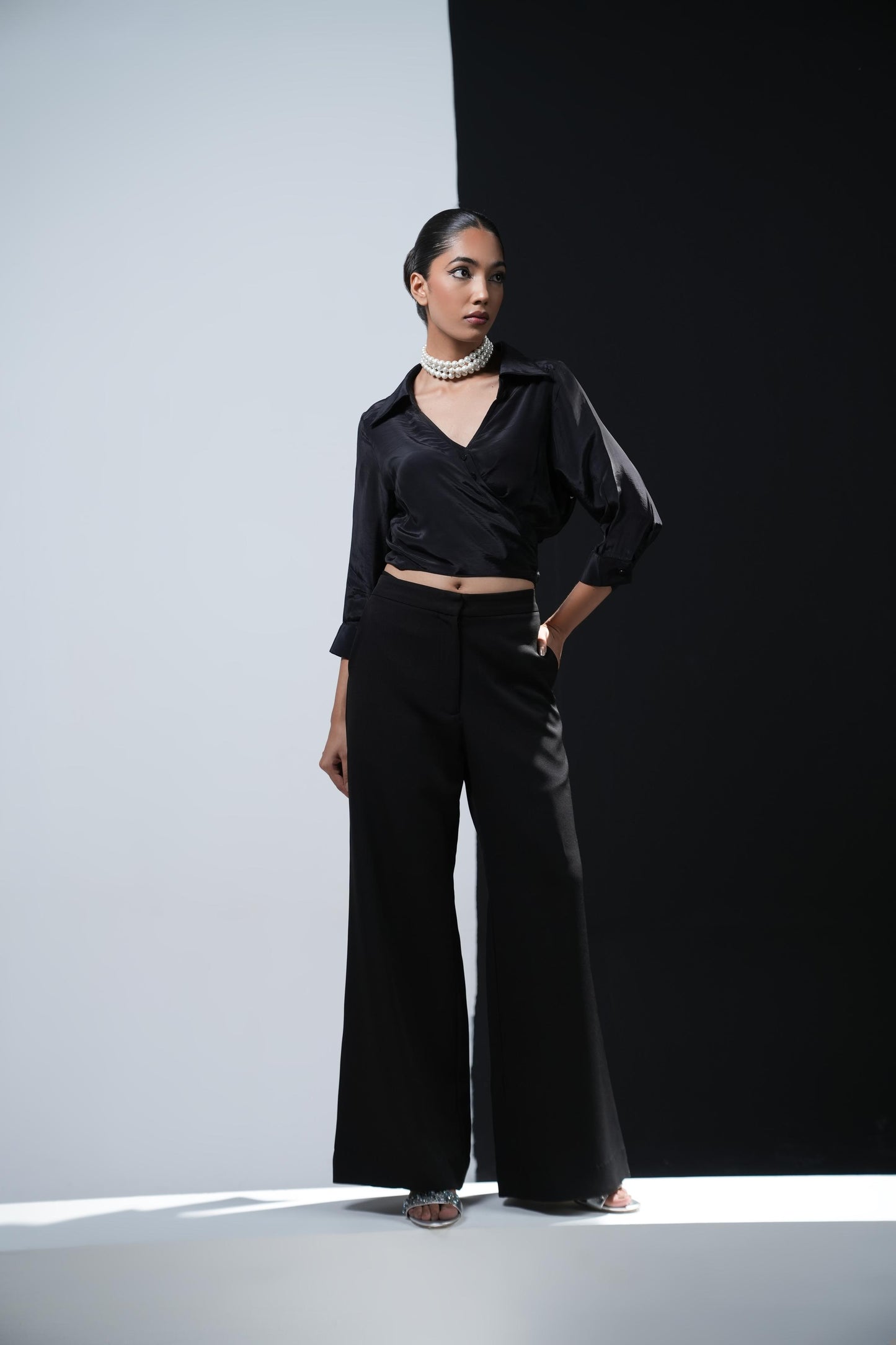 Black crepe overlapping shirt with a long bow paired with black trousers with swaroski pockets