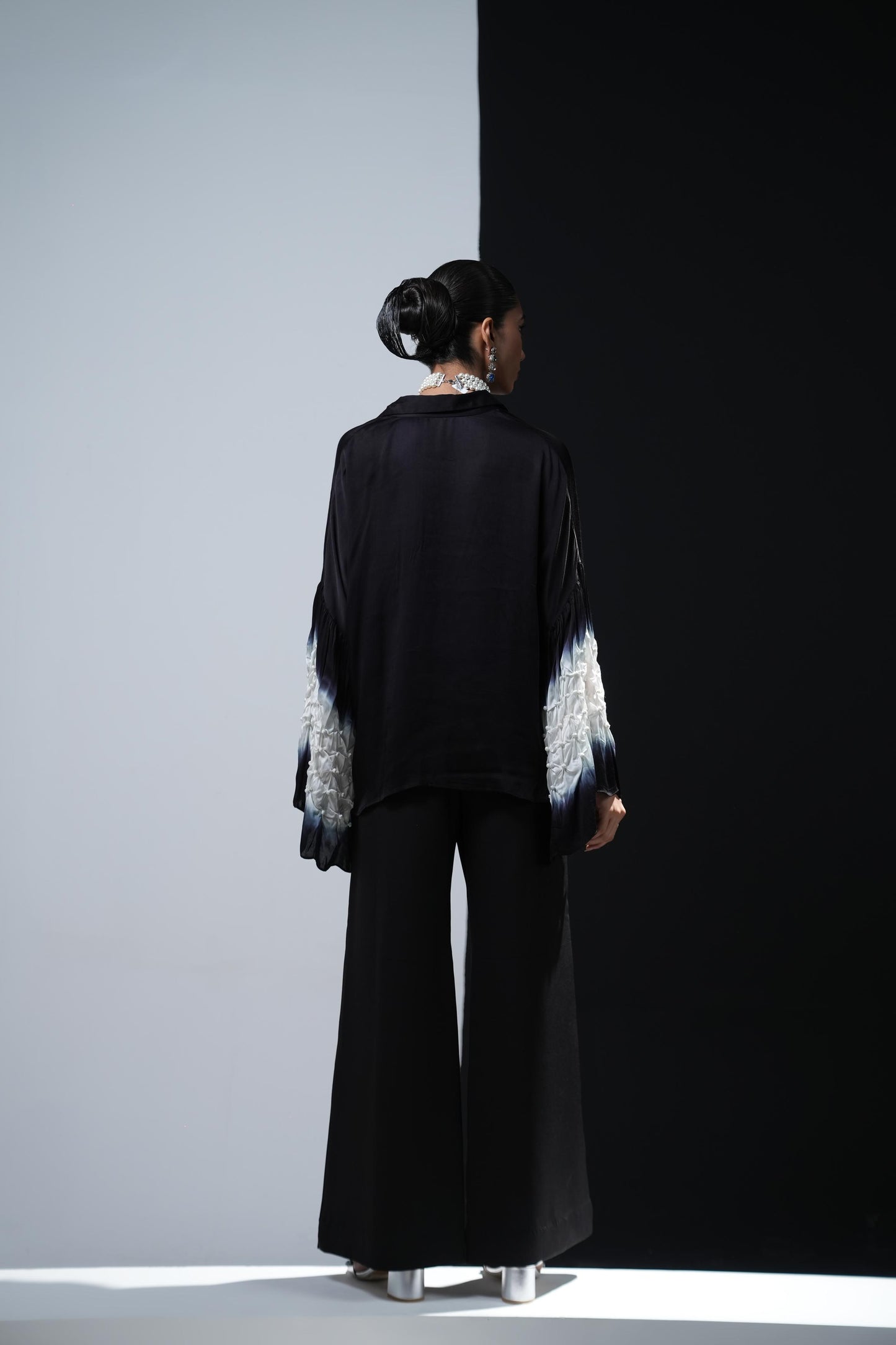 Black satin shirt with white shibori work on the sleeves paired with black bootcut trousers
