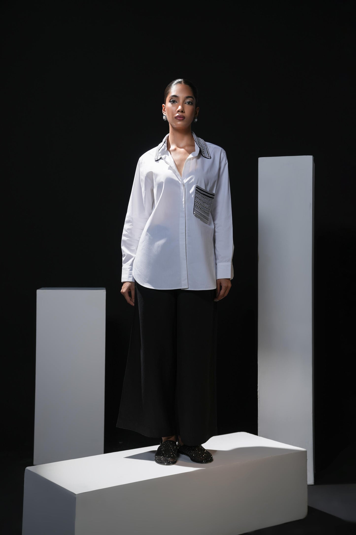 White cotton shirt with pearl detailing on pocket and collar paired with black trousers
