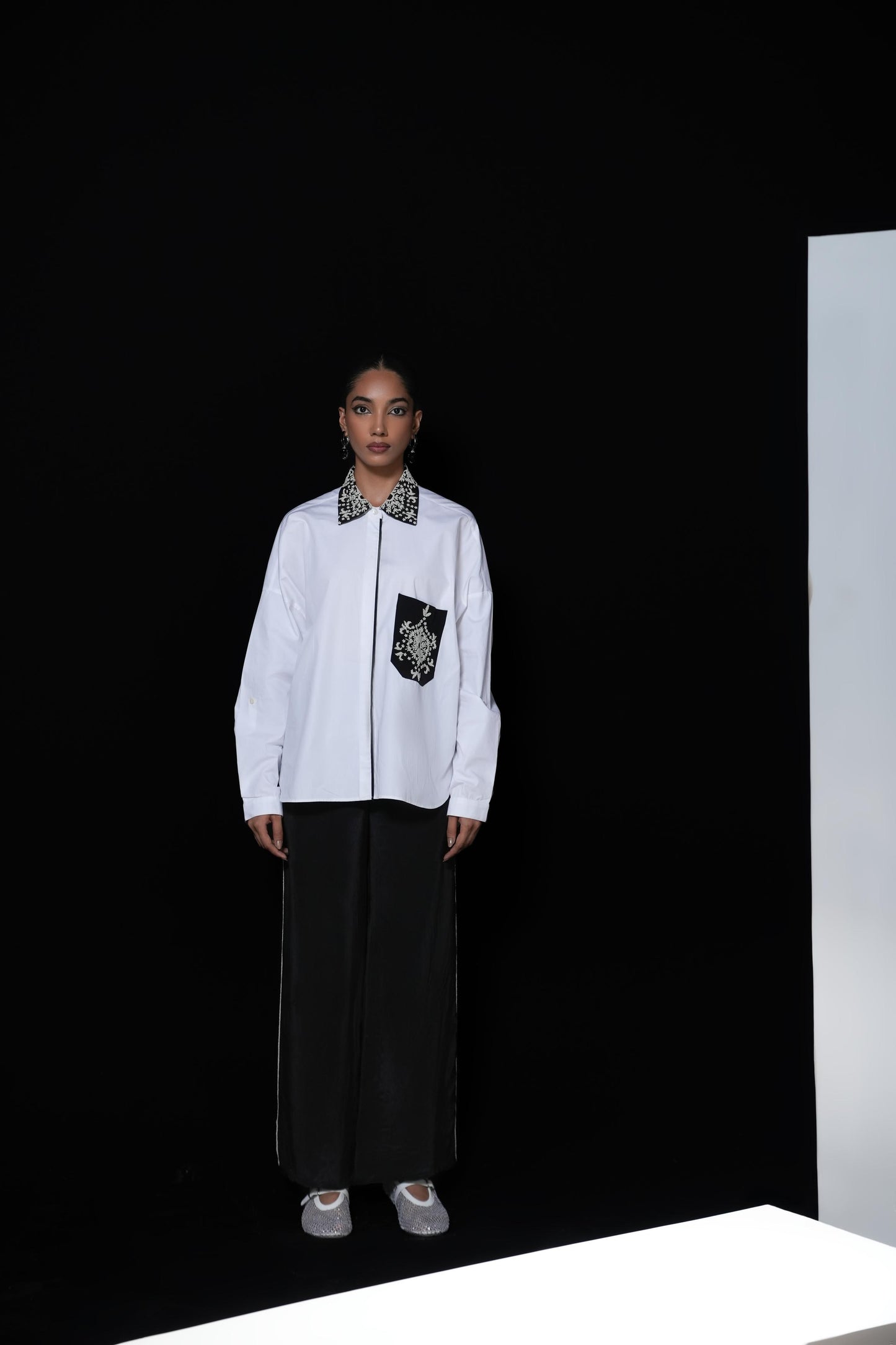White cotton shirt with pearl detailing on pocket and collar paired with black trousers
