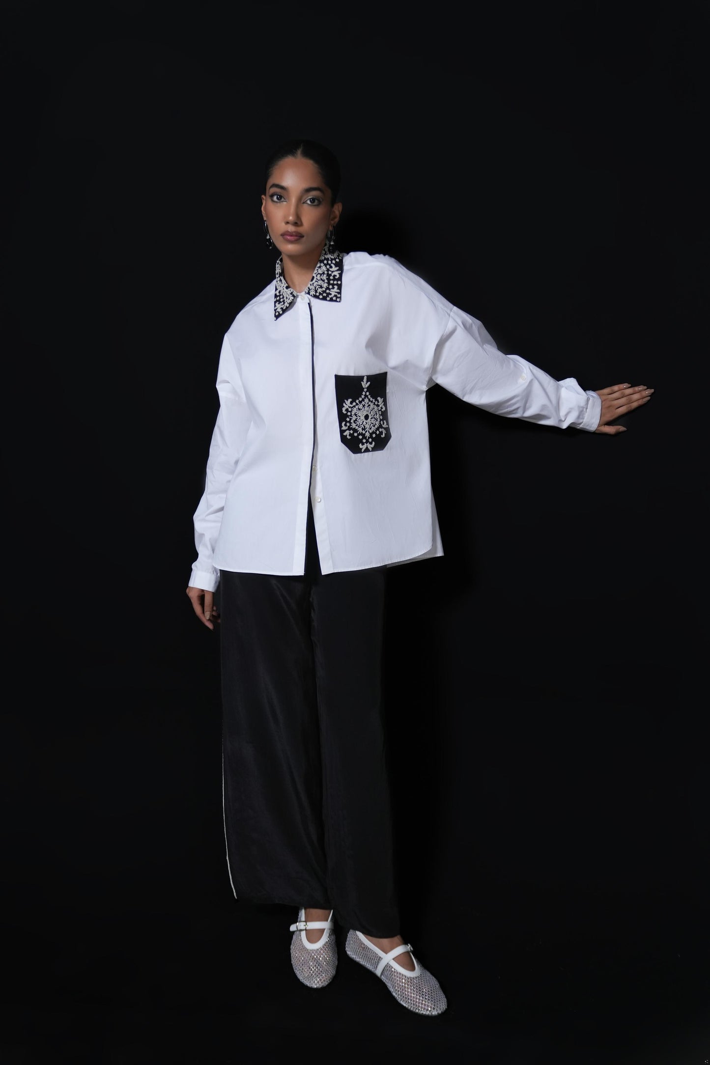 White cotton shirt with pearl detailing on pocket and collar paired with black trousers
