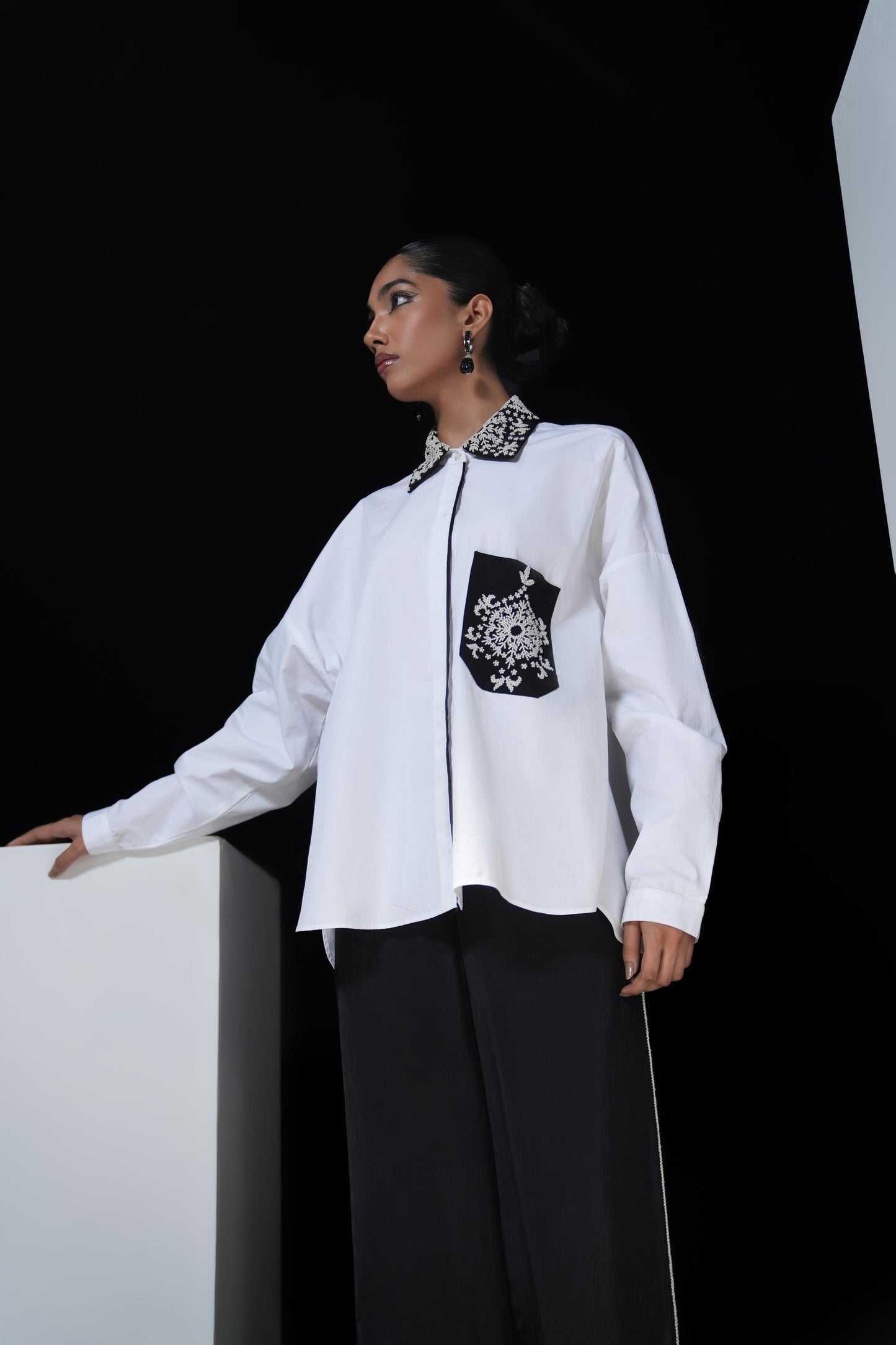 White cotton shirt with pearl detailing on pocket and collar paired with black trousers