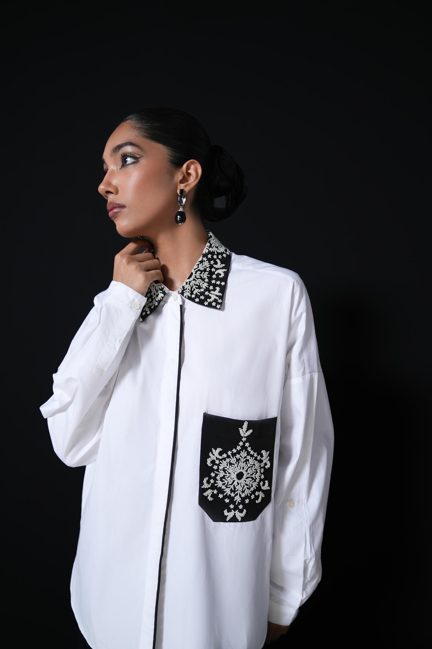 White cotton shirt with pearl detailing on pocket and collar paired with black trousers