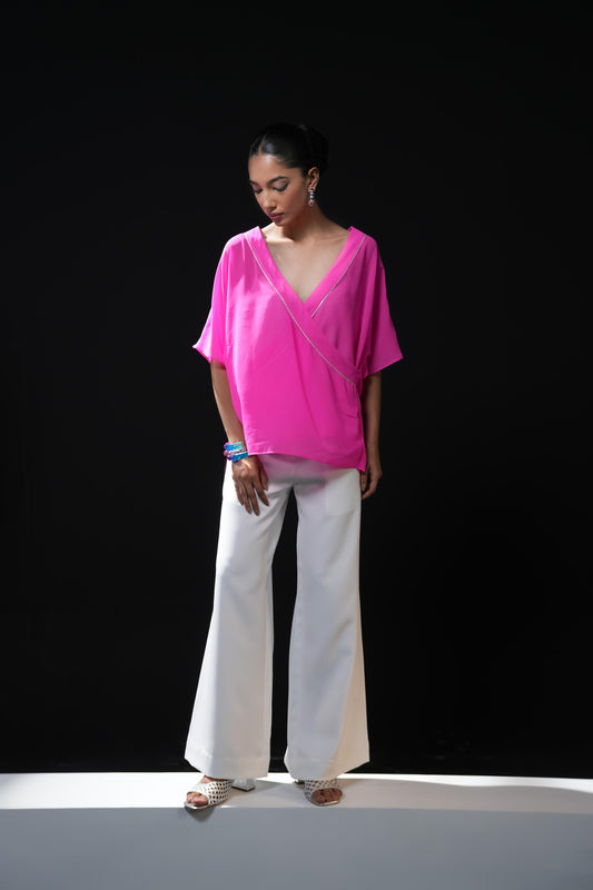 Neon pink free flowing shirt with silver detailing paired with white trousers