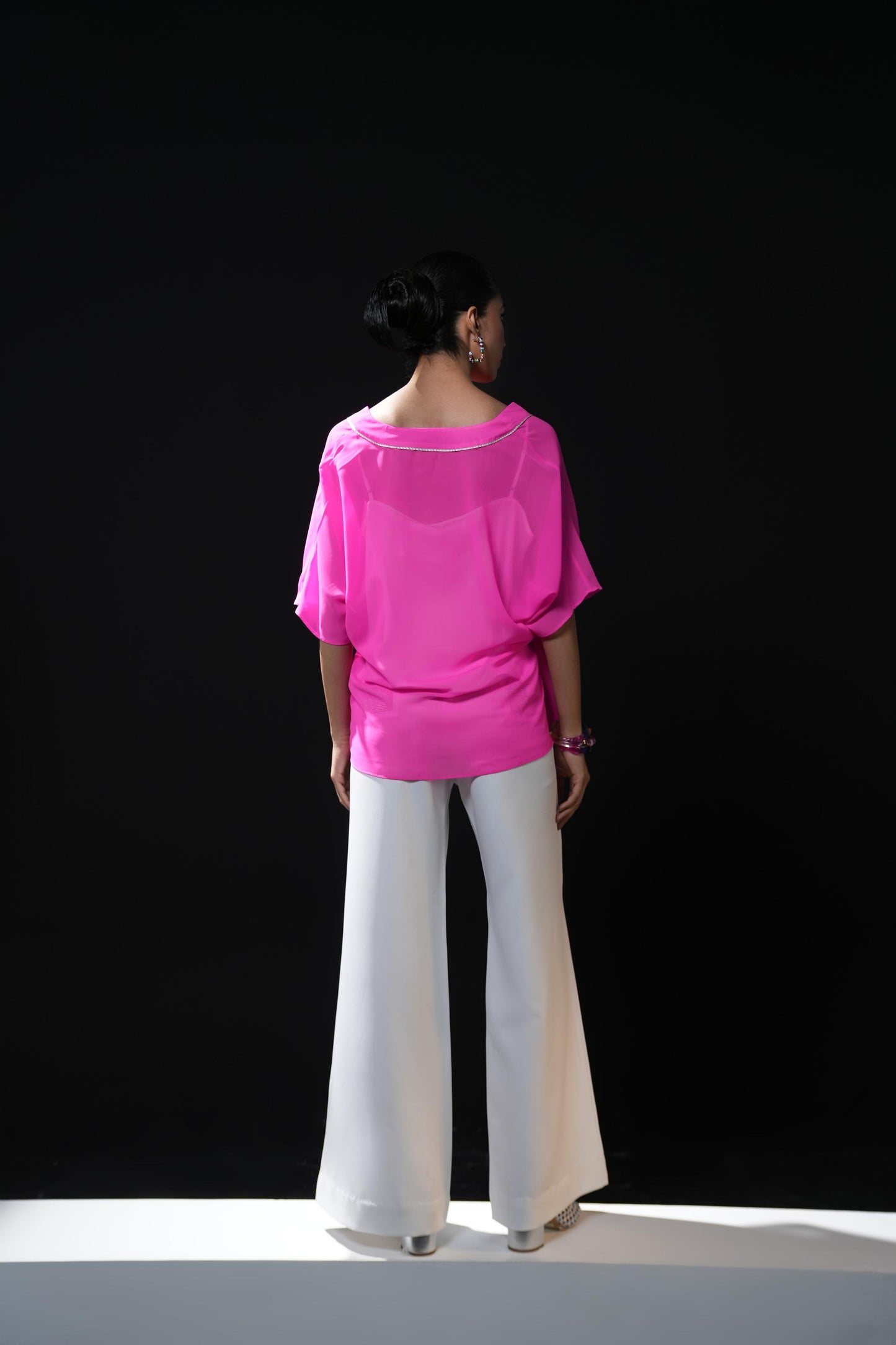 Neon pink free flowing shirt with silver detailing paired with white trousers