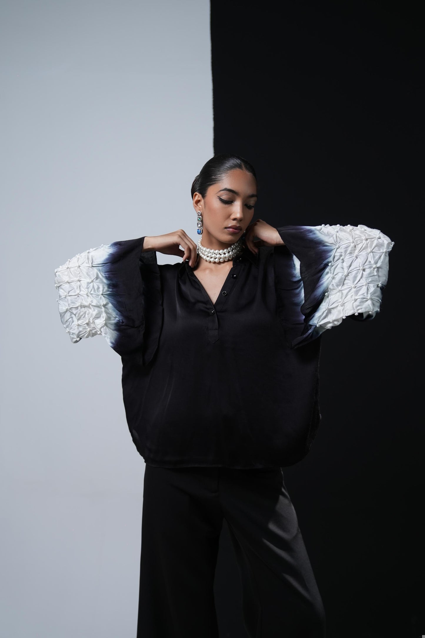 Black satin shirt with white shibori work on the sleeves paired with black bootcut trousers
